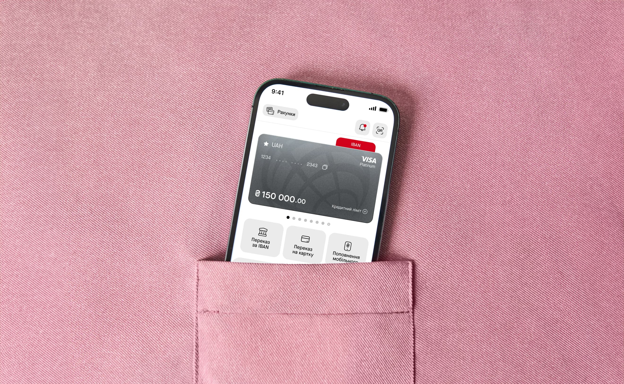 Смартфон із відкритою головною сторінкою застосунку ProCredit Bank стирчить із кишені рожевої тканини. Смартфон із відкритою головною сторінкою застосунку ProCredit Bank стирчить із кишені рожевої тканини.